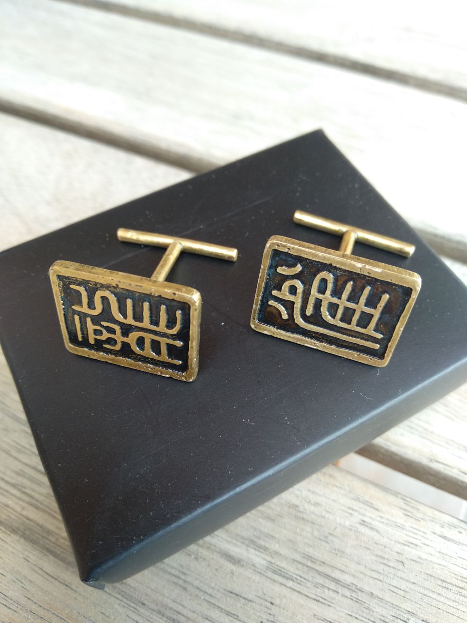 Un par de gemelos de laton con el ideograma de dragón y gorrión respectivamente