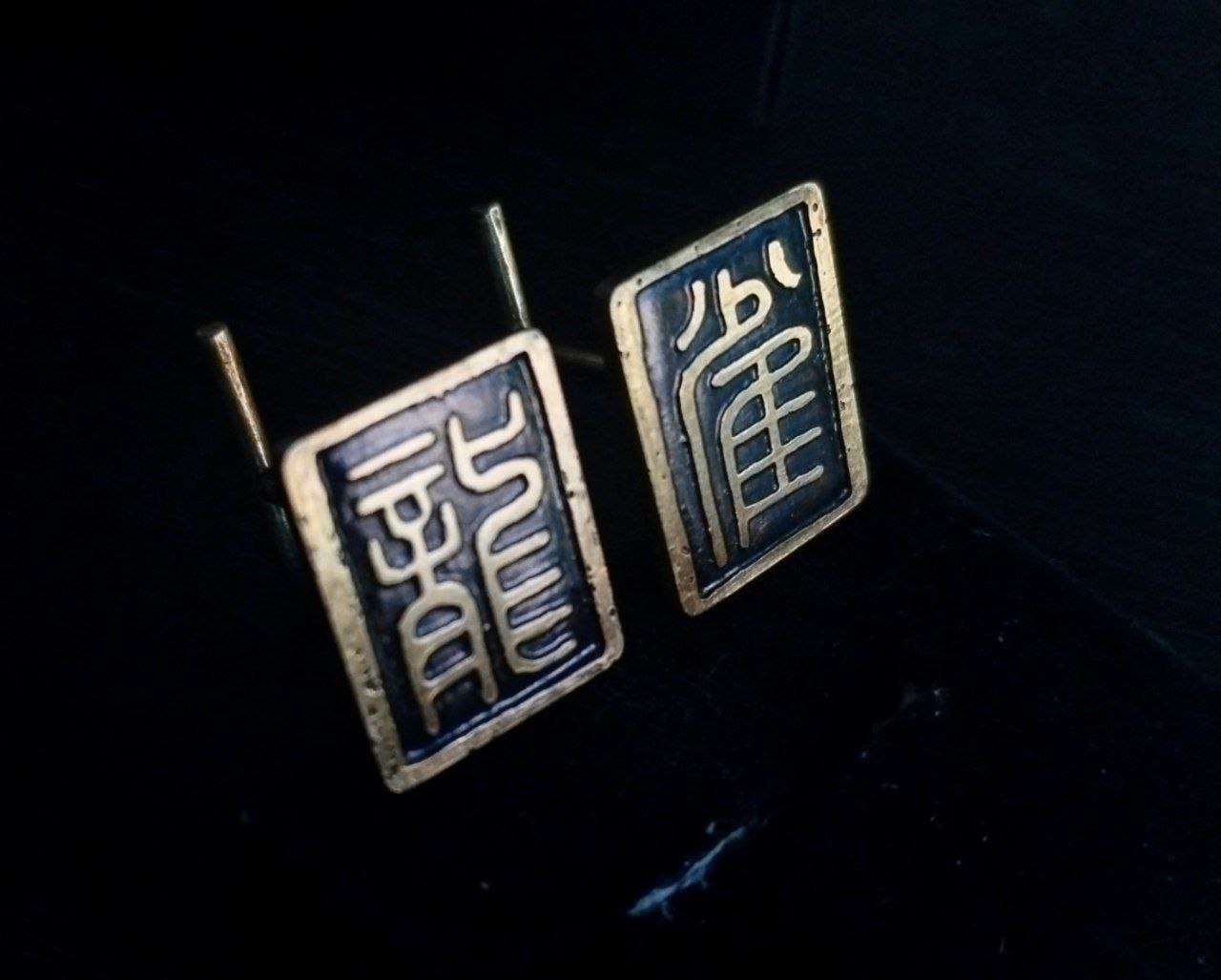 Un par de gemelos hechos a mano en latón con dos ideogramas orientales